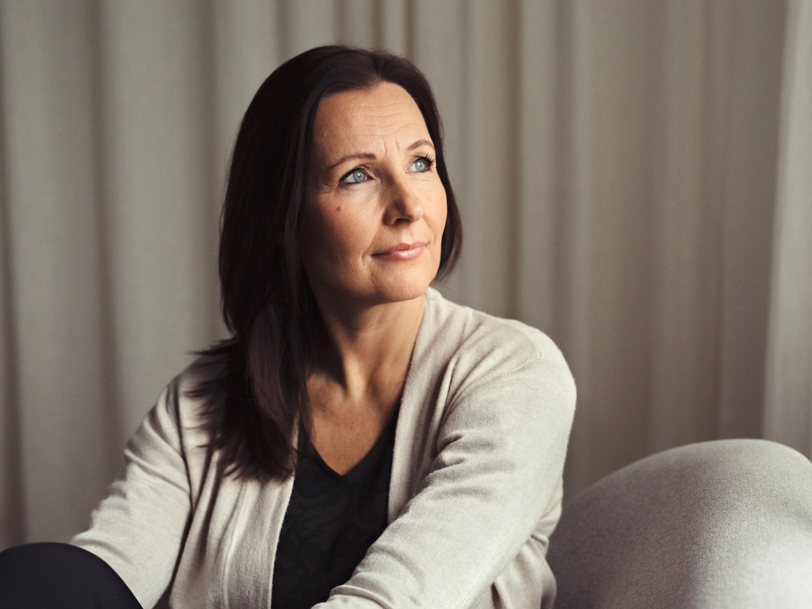 Piia Pihlajamaa hymyilemässä lempeästi neutraalilla taustalla.